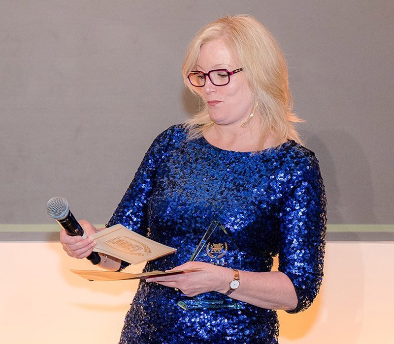 a woman in a blue sparkly dress presenting an award